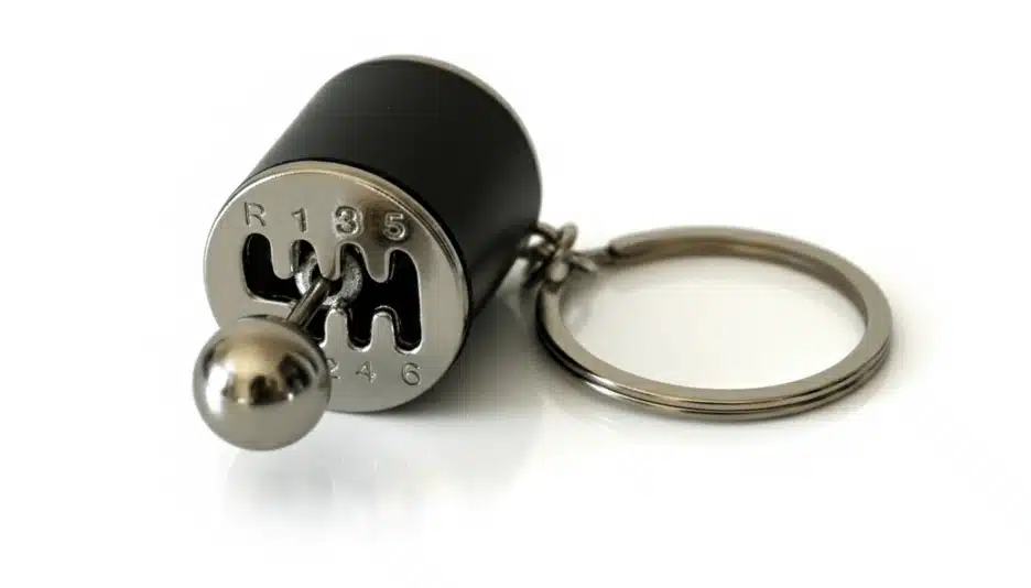 A metal gear knob keychain with a visible H-pattern and working shifter.