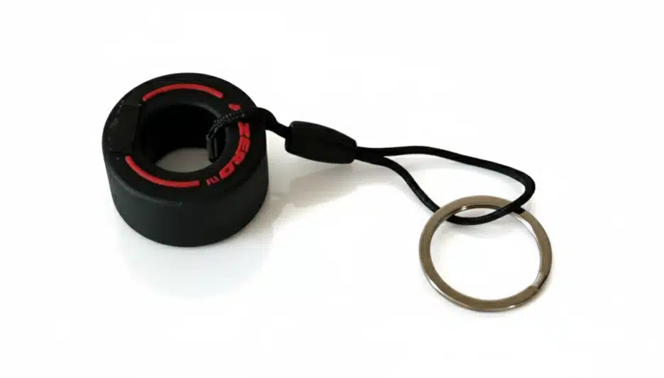 A black soft rubber racing tire keychain with visible tread patterns and brand text.