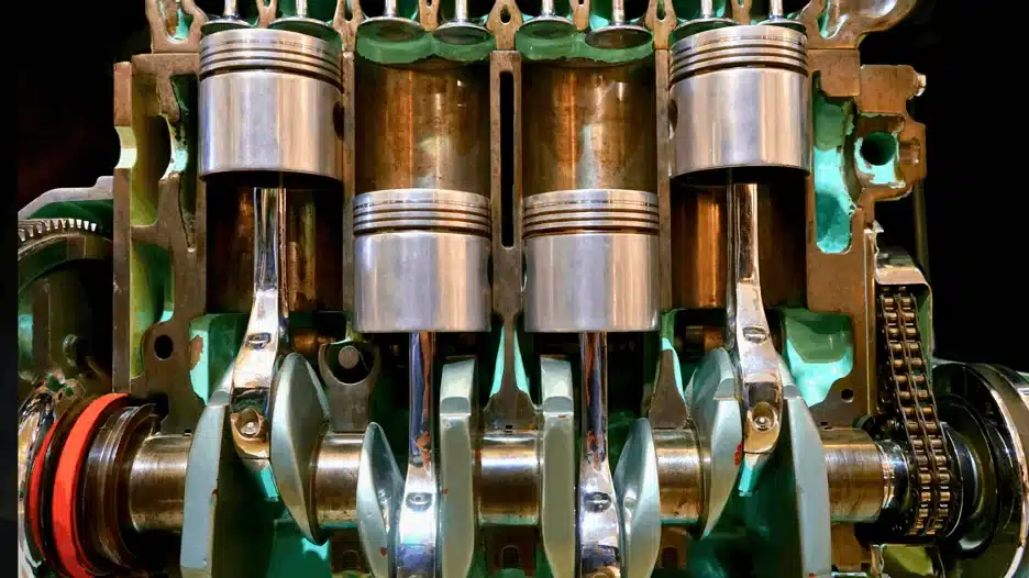 Cross-sectional view of a four-cylinder internal combustion engine showing pistons, connecting rods, crankshaft, and timing chain inside the engine block, showing how engine works.