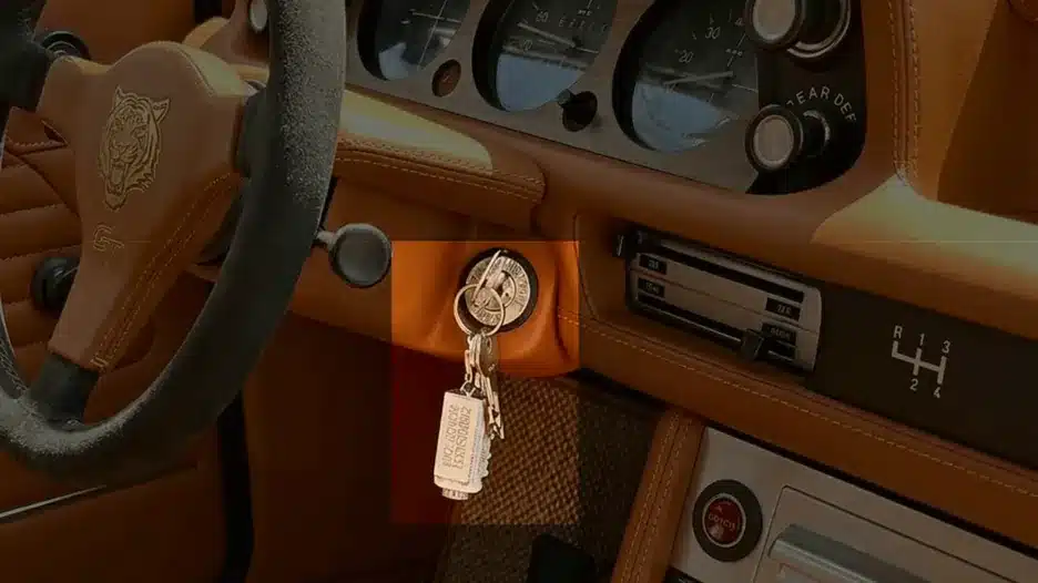 Automotive engine block keychain with chain ring attached displayed inside a car ignition as a stylish car enthusiast accessory.