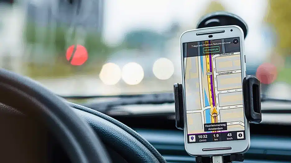 Smartphone mounted on car dashboard displaying GPS navigation map while driving.
