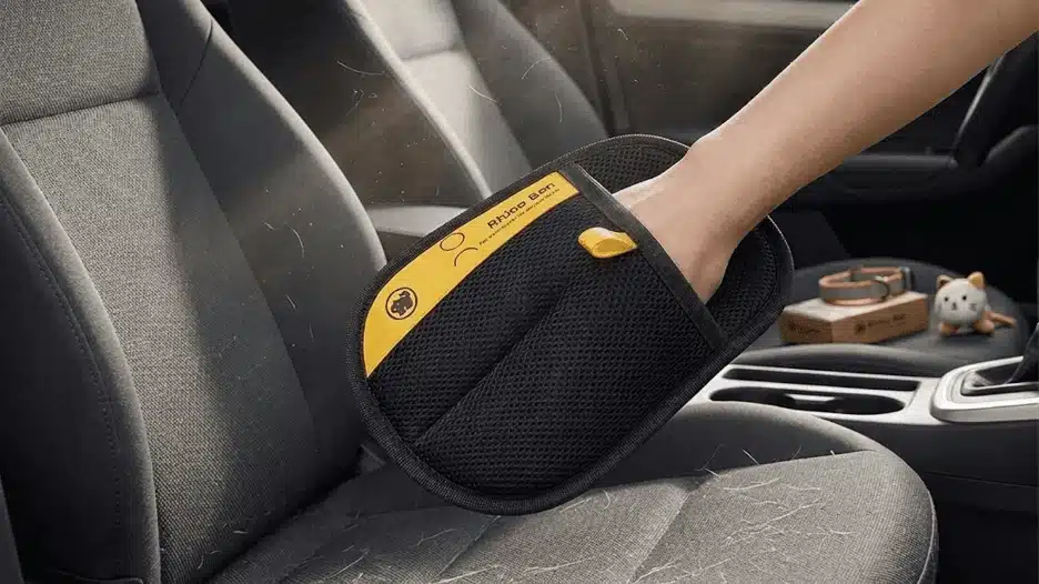 Pet hair removal glove cleaning car seat fabric by lifting embedded fur and debris from upholstery inside vehicle interior.