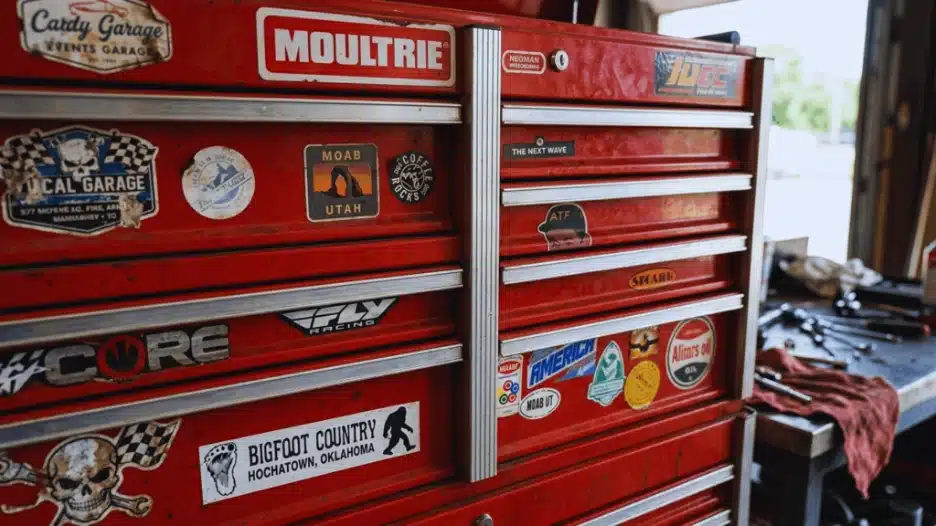 Red tool box covered with assorted automotive brand stickers and decals.