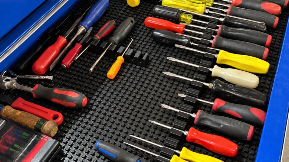 Magnetic toolbox drawer organizer holding multiple screwdrivers in separate positions on a black textured drawer mat inside a blue tool chest.
