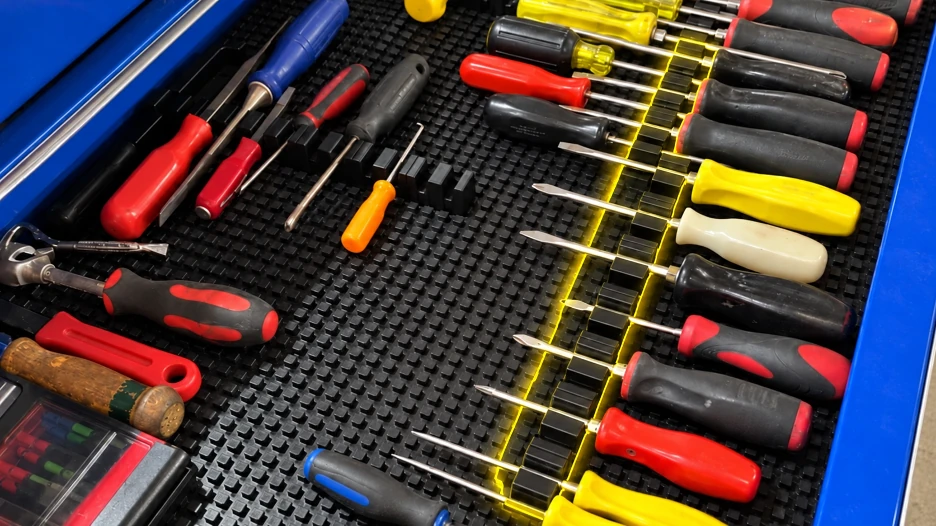 Screwdrivers arranged in rows on a black modular toolbox mat, showing how magnetic screwdriver holders keep different screwdriver sizes organized and easy to find.